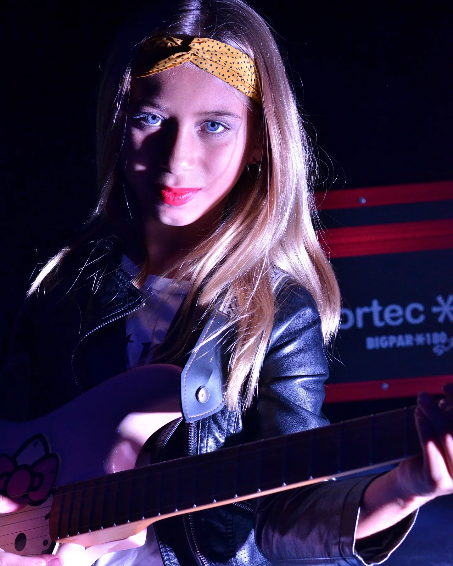 Retrato en estudio con guitarra eléctrica, campera de cuero y luz azul