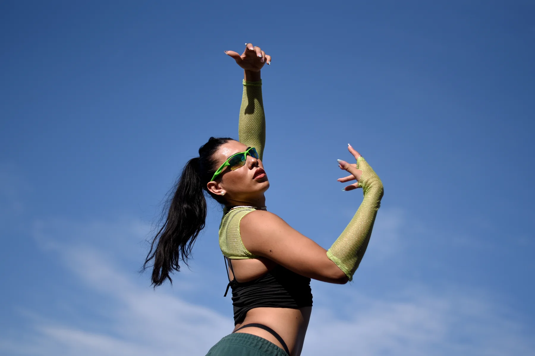 Bailarina de danzas urbanas con los brazos en alto contra el cielo